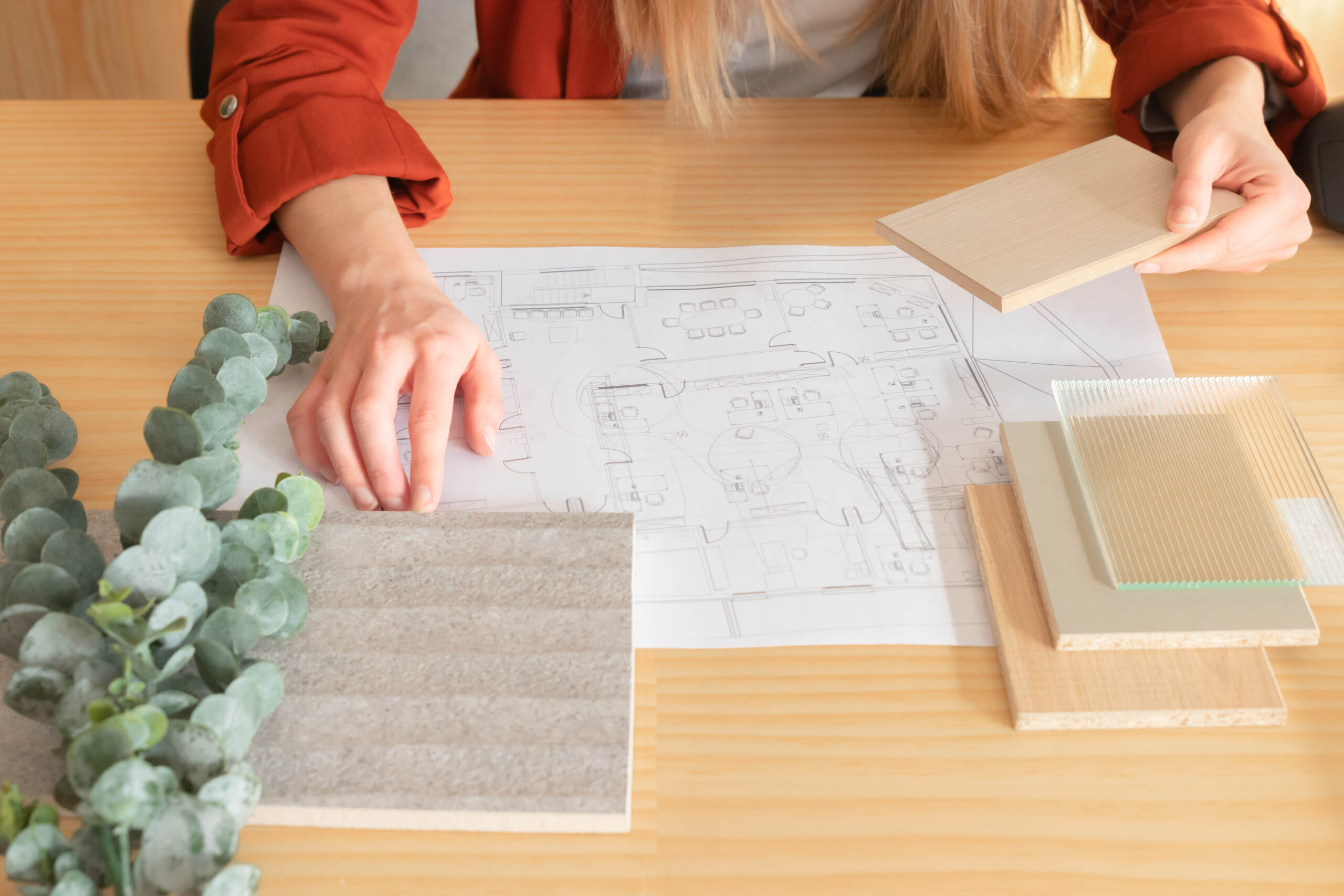 Close up view of woman touching composition of different materials in interior design with floor plans and plants around